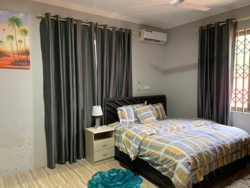a bedroom with a bed with black drapes at FranGee gold house with cool breeze & solar backup in Kpomkpo