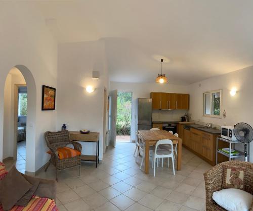 a kitchen and living room with a table and chairs at Maison récente entre mer et montagne in Figari