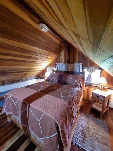 a bed in a room with a wooden ceiling at Chalé Fazendinha in Bocaina de Minas
