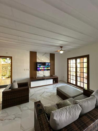 a living room with a couch and a tv at Casa Tortuga 5 suítes 400 metros da praia in Guarujá