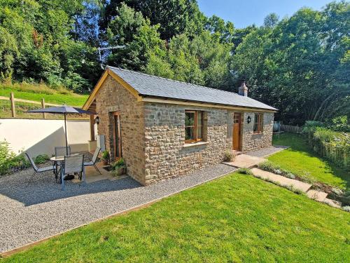 a small stone cottage with a table and a bench at Thornycroft Cottage in Llanvair Discoed