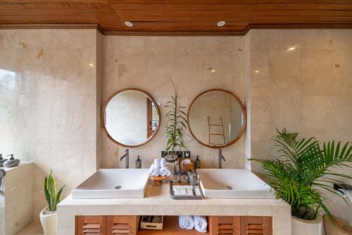 a bathroom with two sinks and two mirrors at The Lumbung Jaya Resort in Tegalalang