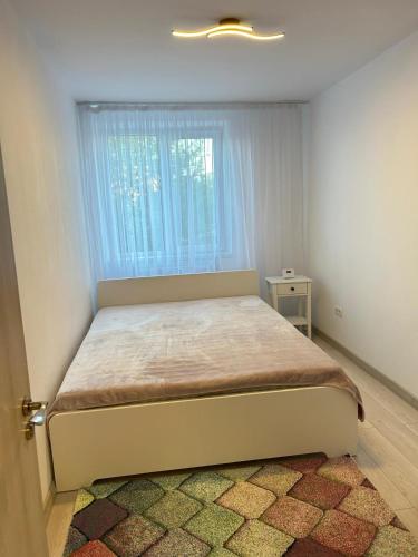 a bedroom with a bed with a window and a rug at Apartament Tomis Nord in Constanţa