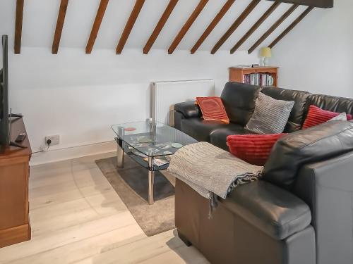 a living room with a leather couch and a glass table at Meifod Coach House in Denbigh