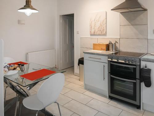 a kitchen with a table and a stove top oven at Meifod Coach House in Denbigh