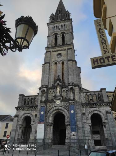 a church with a tower with a clock on it at Capstay Lourdes - Residence Serenity in Lourdes