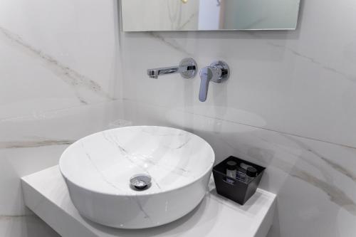 a white bathroom with a sink and a mirror at Hotel Diana in Koroni