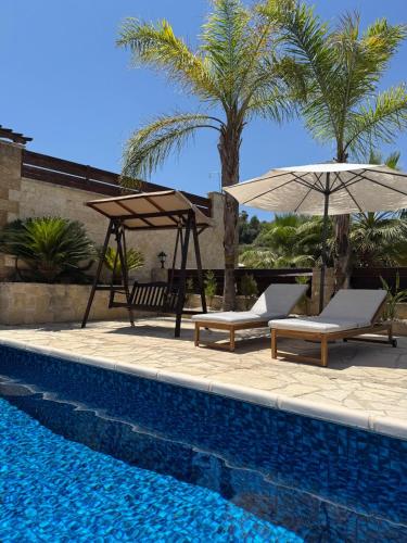two chairs and umbrellas next to a swimming pool at Stunning Traditional Stone Villa - Kallepia in Kallepia