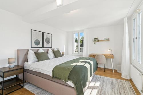a white bedroom with a large bed and a desk at Klara 1022 - Olma, Spital, Uni St- Gallen in St. Gallen