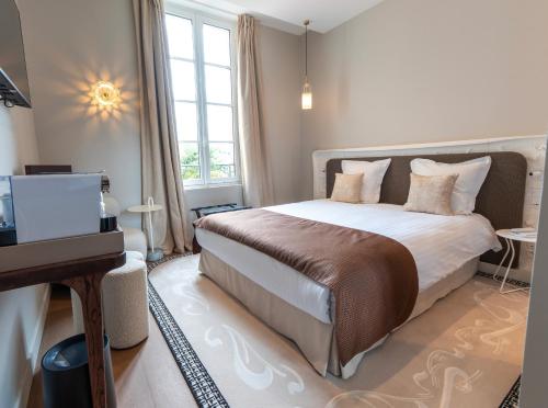 a bedroom with a large bed and a television at Hôtel des Arts in Angoulême