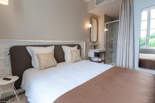 a bedroom with a large white bed with pillows at Hôtel des Arts in Angoulême