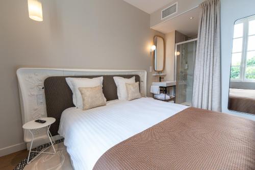 a bedroom with a large white bed with pillows at Hôtel des Arts in Angoulême