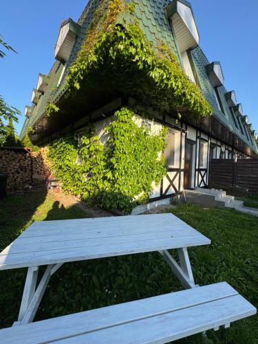 a white bench sitting in front of a building at Corner House Plesna in Pleśna
