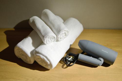 a pile of towels on a table next to a hair dryer at Hotel KOTO in Sapporo