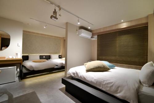 a bedroom with two beds and a desk and a mirror at Hotel KOTO in Sapporo