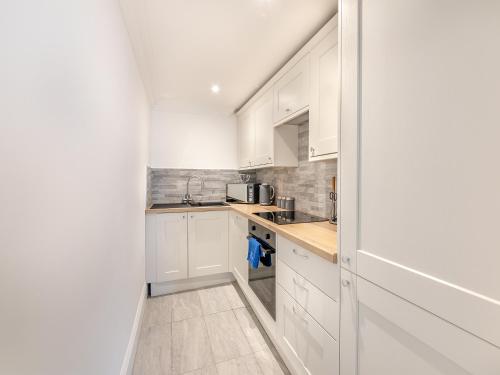 a white kitchen with white cabinets and a sink at Iris Apartment - Uk45966 in Yarm