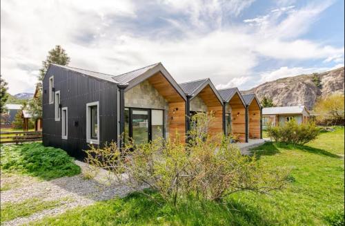 a house with a black facade and wood at El Filo Aparts de Montaña in El Chalten