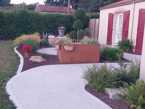 a walkway in a yard with potted plants and a house at chambre d'hôte chez Mimidid in Le Landreau