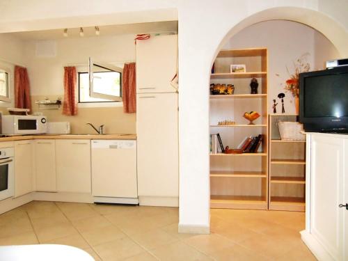 une cuisine avec des placards blancs et une télévision dans la chambre. dans l'établissement Mare a Mare, à Porto-Vecchio