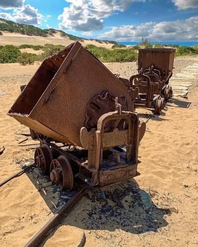 two old trucks are sitting in the sand at Borgo Ingurtosu in Ingurtosu