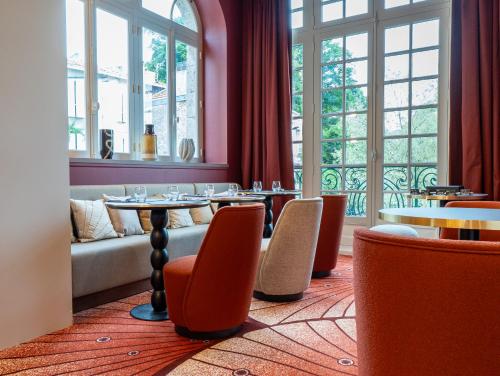 a restaurant with tables and chairs and windows at Hôtel des Arts in Angoulême