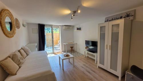 un salon avec un canapé blanc et une télévision dans l'établissement Studio avec terrasse et vrai lit 160x200cm, indépendant calme absolu dans maison de famille, à La Valette-du-Var