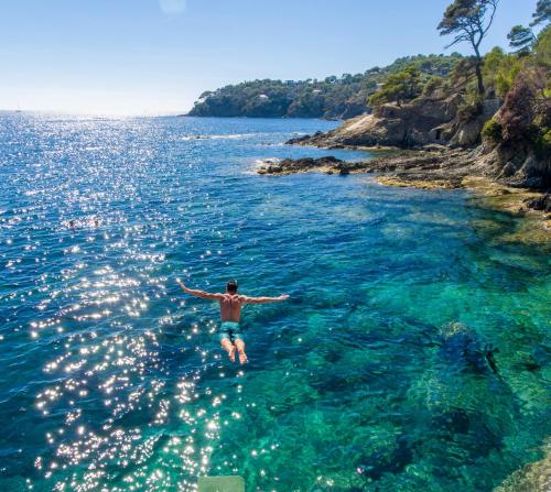 a man is swimming in the water at Hôtel Le Provençal - Rénové en 2025 - Bord de Mer in Hyères