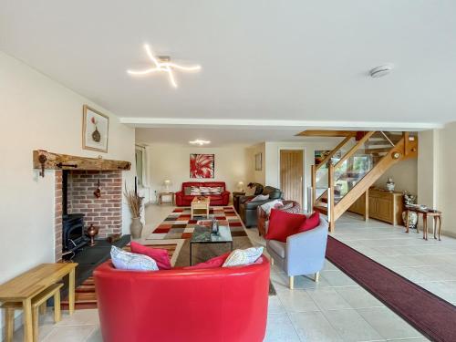 a living room with red chairs and a fireplace at Hill Farm Barn in Damerham