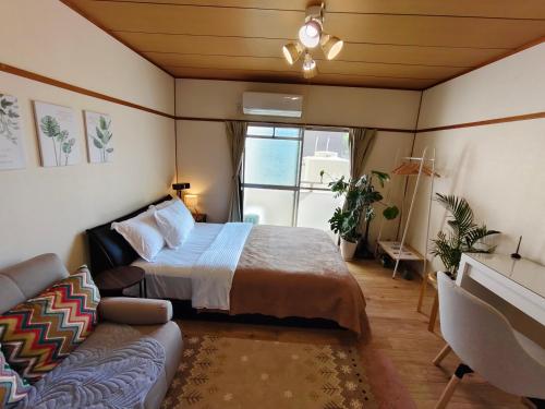 un dormitorio con una cama y un sofá en ゲストハウスDiDi, en Tokushima