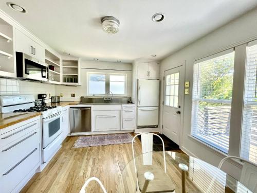 オースティンにあるDeep Eddy 2/1 Bungalow + Fenced Yard!のキッチン(白い家電製品、ガラスのテーブル付)