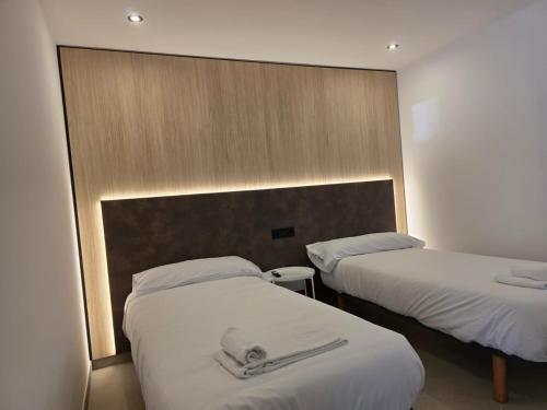 two beds in a hotel room with white sheets at Apartamentos Camino Inglés II in Ordes