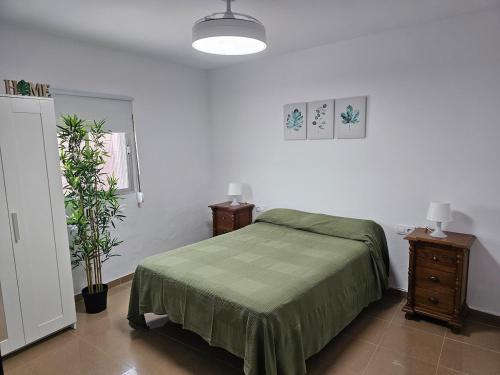 a bedroom with a bed with a green blanket at La Casita in Chiclana de la Frontera
