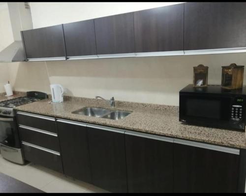 a kitchen with a sink and a microwave at Departamento Caseros in Salta