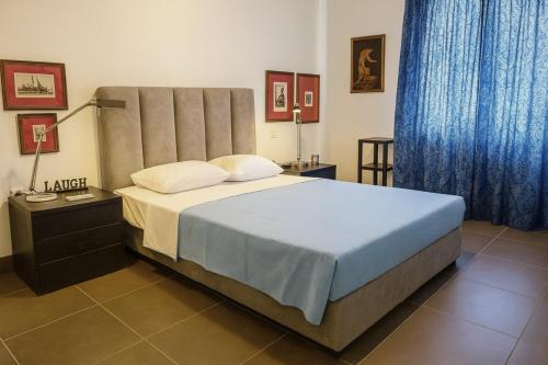 a bedroom with a large bed with blue curtains at Verdant Escape Corfu in Corfu