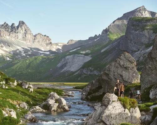 a group of people standing on rocks next to a river at Mountain View - Trek, Bike, Ski, Lake in Flims