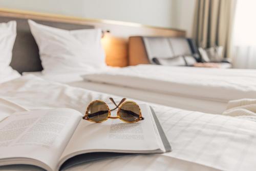 a pair of sunglasses sitting on a book on a bed at Boutique Hotel Zach in Innsbruck