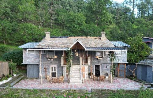 an old house with a roof on a patio at Aikkya Farms in Mukteswar