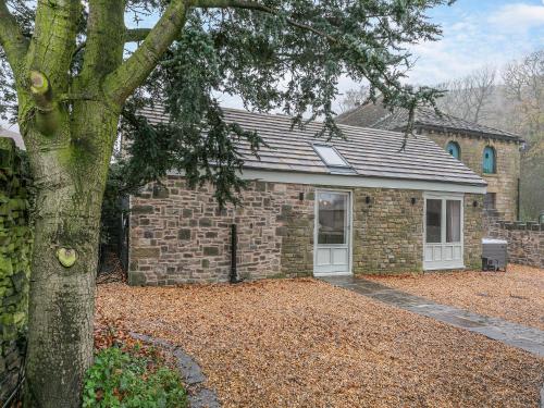 a brick house with a tree in front of it at Syke Farm Cottage in Littleborough