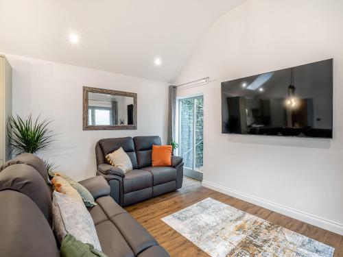 a living room with a couch and a flat screen tv at Syke Farm Cottage in Littleborough