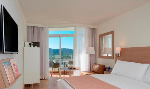 a hotel room with a bed and a large window at Meliá Calviá Beach in Magaluf