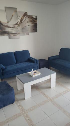un salon avec une table basse blanche et des canapés bleus dans l'établissement Appartements Au Cros De Cagnes, à Cros-de-Cagnes