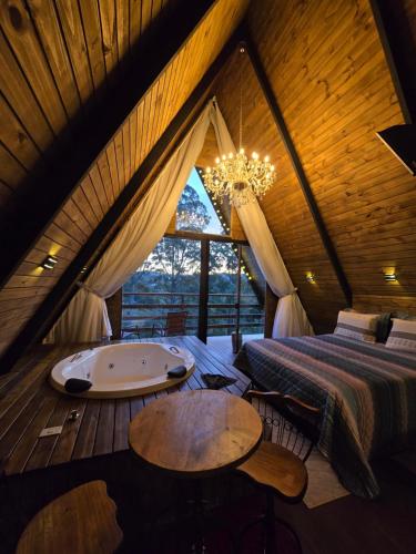 a bedroom with a tub and a bed and a window at Chalés Capivari Cristal in Campos do Jordão