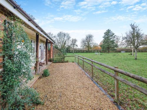 a house with a fence next to a field at Paddock Barn in North Nibley