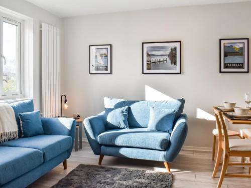 a living room with a blue couch and a chair at Hillside At Bowness in Windermere