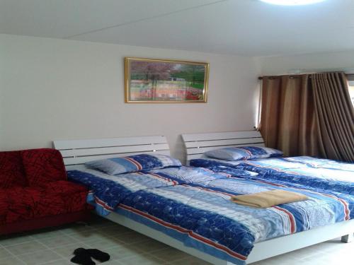 a bedroom with two beds and a red chair at Smart Residence@Muengthongthani in Nonthaburi