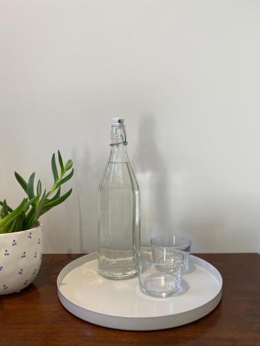 une bouteille en verre sur une assiette avec deux verres dans l'établissement Chambre d'Hôtes Dahlia - Boutenac, à Boutenac