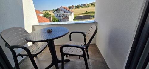 a small table and chairs on a balcony with a view of a house at Hotel Pojata in Gjilan