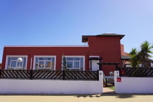 a red house with a white fence in front of it at Banama Coliving & Coworking, Surf & Yoga - Casa Roja in Corralejo