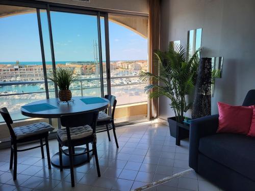 - un salon avec une table, des chaises et une grande fenêtre dans l'établissement Studio 1 bedroom, very nice view with parking space, à Mauguio