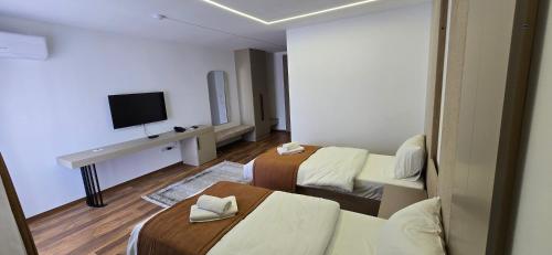 a hotel room with two beds and a flat screen tv at Hotel Pojata in Gjilan